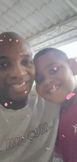 Father and son smiling selfie with pink confetti.