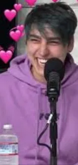 Smiling person with purple hoodie surrounded by pink hearts.