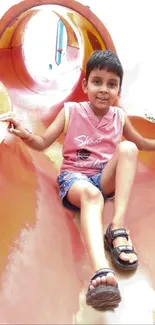 Child enjoying a slide on a colorful playground.