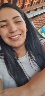 Smiling woman in a natural setting, indoors, with long hair and white shirt.