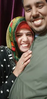 Smiling couple in colorful clothing with a vibrant background.