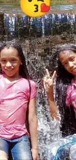 Two girls enjoying a waterfall with joyous smiles and peace signs.