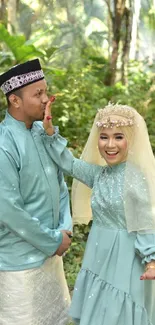 Bride and groom dressed in teal, celebrating in a lush, green outdoor setting.