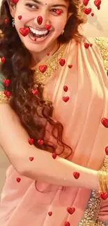 Smiling woman in peach saree adorned with red hearts.