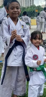 Children posing in karate uniforms outdoors.