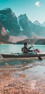 Person kayaking on turquoise lake with mountains in background.