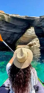 Woman kayaking in turquoise waters with rocky cliffs view.