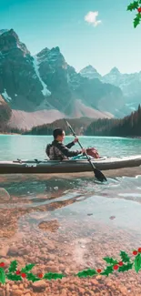 Person kayaking in a turquoise mountain lake with festive holly accents.