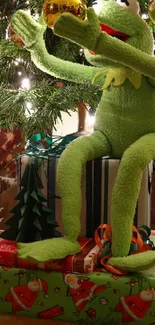 Kermit decorates a Christmas tree with gifts below.