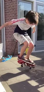 Child skateboarding on patio with brick wall backdrop.