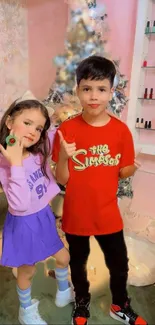 Two children posing in a cozy, festive winter-themed room.