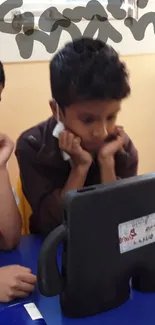 Children interacting with a tablet in a colorful classroom setting.