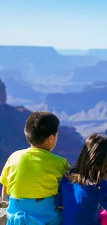 Children sitting overlooking a stunning canyon view with blue skies.