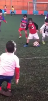 Kids playing soccer indoors on a vibrant field.