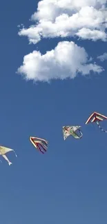 Colorful kites flying against a blue sky with clouds.