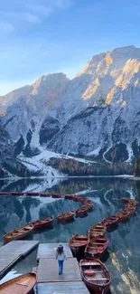 Serene lake with boats and snowcapped mountains background.