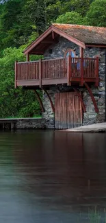 Stone cabin by a tranquil lake with lush greenery and clear blue sky.