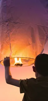 A child releases a glowing lantern into the colorful evening sky.