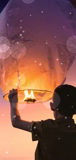 Child launches glowing lantern at sunset with a scenic sky.