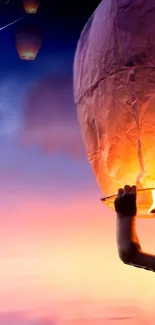 Sky lanterns glowing against a twilight sky with a colorful sunset gradient.