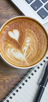 Latte art on coffee with notebook and pen on a wooden desk.