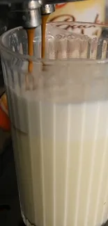 Creamy coffee latte being poured into glass.