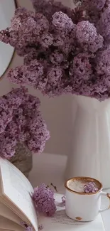 Lilac flowers in a vase with an open book and coffee cup.