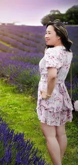 Woman in floral dress in lavender field at sunset.