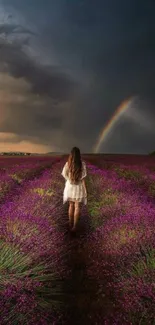 A woman walks in a lavender field under a rainbow-filled sky.