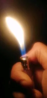 Hand holding a lighter with a bright flame in the darkness.