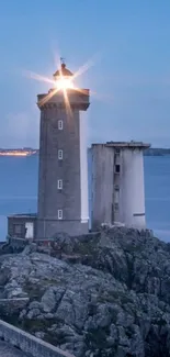 Lighthouse at dusk with calm sea and glowing light.