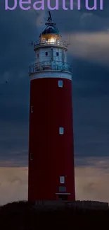 Lighthouse standing in front of a dramatic dark blue evening sky.