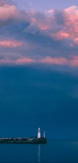 Lighthouse with pink sunset clouds over blue ocean.