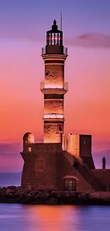 Lighthouse at sunset with vibrant colors in the sky and reflecting water.