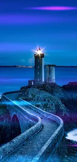 Lighthouse illuminated at night over a serene blue ocean.