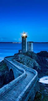 Serene lighthouse by the ocean at dusk with a vibrant blue sky.