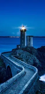 Serene lighthouse by the ocean at night with a starry sky.