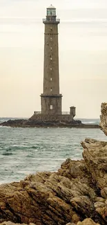 Lighthouse stands amid rocky coastline with serene sea and sky.