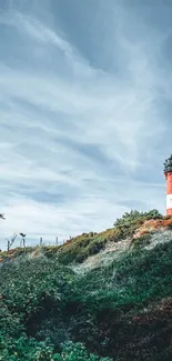 Lighthouse on a scenic coastal hill under a blue sky.