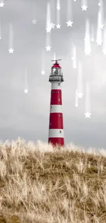 Red and white lighthouse with dune grass under a cloudy sky.