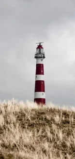 Red lighthouse stands tall under a dynamic sky.