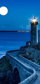 Lighthouse with moon in deep blue night sky and calm ocean view.