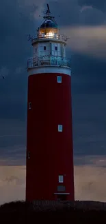 Red lighthouse against a dramatic dark blue sky at dusk.