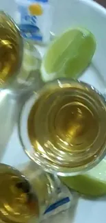 Tequila shots with lime wedges on a plate.