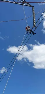 Lineman working on power lines against a blue sky backdrop.