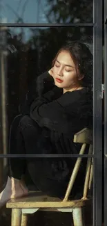 Woman seated inside, seen through a window frame.