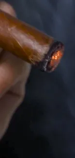 Close-up of a lit cigar with glowing ember on a dark background.