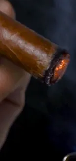 Close-up of a lit cigar with glowing embers and smoke.