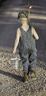 Young boy with bucket and fishing pole on gravel path.