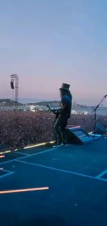 Guitarist performing on stage at sunset with a vibrant crowd.